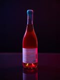 Bottle of orange wine with a blue wax tip on a dark background